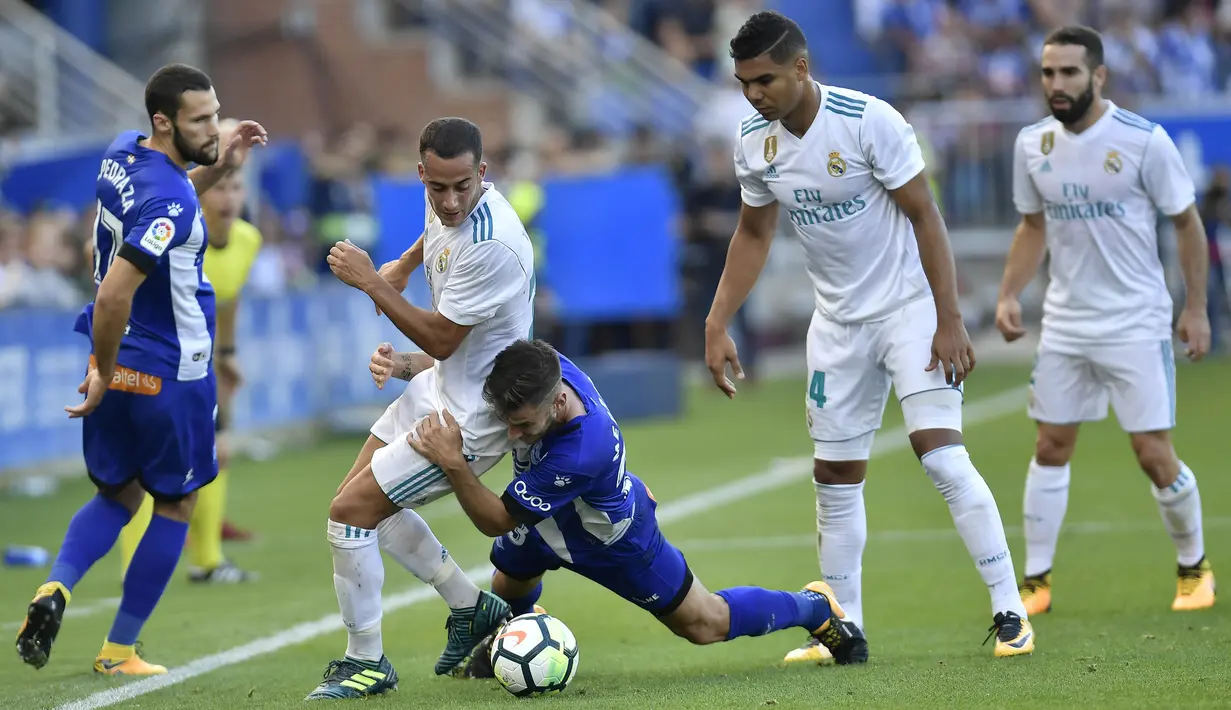 Striker Real Madrid, Lucas Vazquez, berebut bola dengan gelandang Deportivo Alaves, Medran, pada laga La Liga di Stadion Mendizorroza, Sabtu (23/9/2017). Real Madrid menang 2-1 atas  Deportivo Alaves. (AP/Alvaro Barrientos)