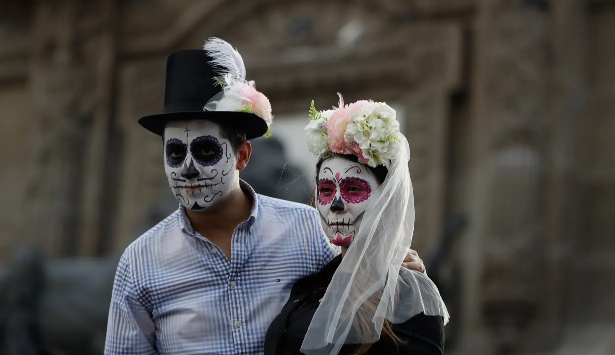 Peserta berkostum tengkorak menunggu dimulainya Prosesi Grand Catrinas, bagian dari Day of The Dead di Mexico City, Minggu (22/10). Puncak perayaan ditandai dengan kunjungan ke makam orang-orang yang dicintai pada 1 dan 2 November. (AP/Rebecca Blackwell)