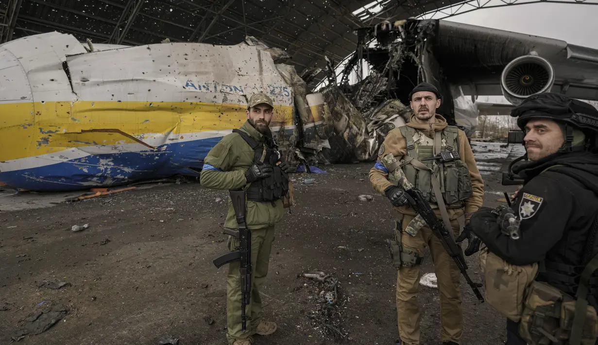 Prajurit Ukraina berdiri dekat pesawat Antonov An-225 Mriya di bandara Antonov di Hostomel, 2 April 2022. Di pintu masuk Bandara Antonov, pasukan menjaga posisinya, tanda mereka memegang kendali penuh atas landasan pacu yang coba diserbu Rusia di hari-hari pertama perang. (AP Photo/Vadim Ghirda)
