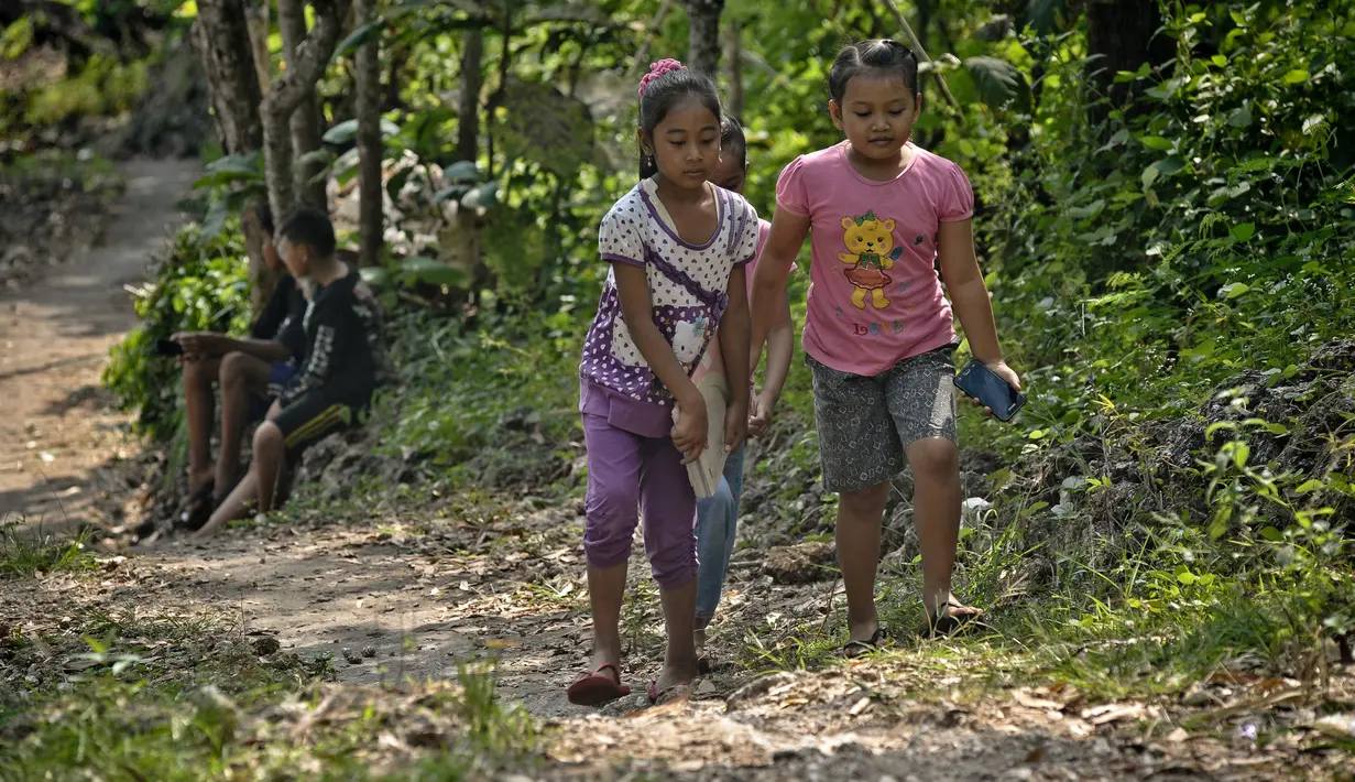 Siswa sekolah dasar mendaki bukit Temulawak mencari sinyal internet sebelum mengikuti pembelajaran secara online menggunakan smartphone di Yogyakarta, Jumat (8/5/2020). Mereka ke atas bukit untuk mendapat sinyal yang bagus agar kegiatan belajar secara online dapat berlangsung. (AGUNG SUPRIYANTO/AFP)