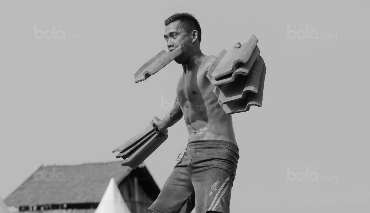 Peserta menunjukan keahliannya mengangkat genteng saat mengikuti kontes binaraga di Desa Jatiwangi, Majalengka, Jawa Barat, (11/8/2017). Kontes yang digelar setiap tahun ini merupakan bagian dari perayaan HUT kemerdekaan RI. (Bola.com/M iqbal Ichsan)