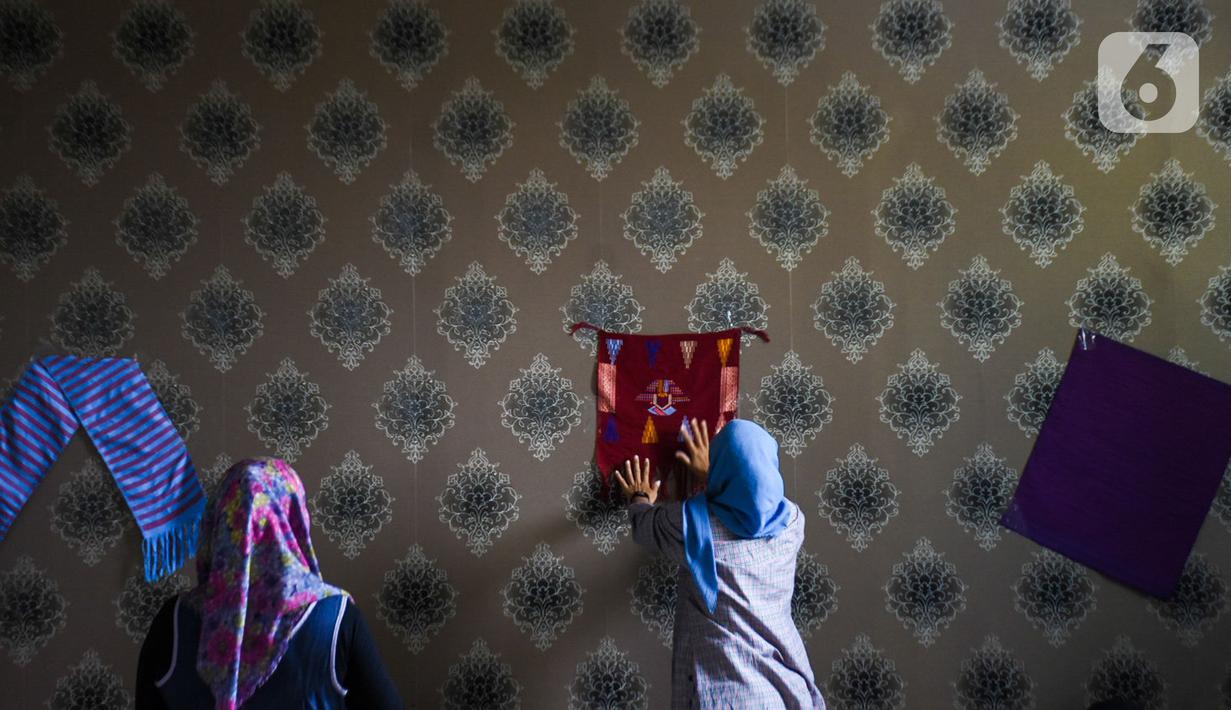 Warga menempelkan kain tenun motif Betawi di Rusunawa Jatinegara, Jakarta, Rabu (13/11/2019). Pemerintah akan memprioritaskan penyaluran  Kredit Usaha Rakyat (KUR) kelompok, seiring dengan diturunkannya suku bunga KUR per 1 Januari 2020 menjadi 6 persen, dari  7 persen. (Liputan6.com/Angga Yuniar)