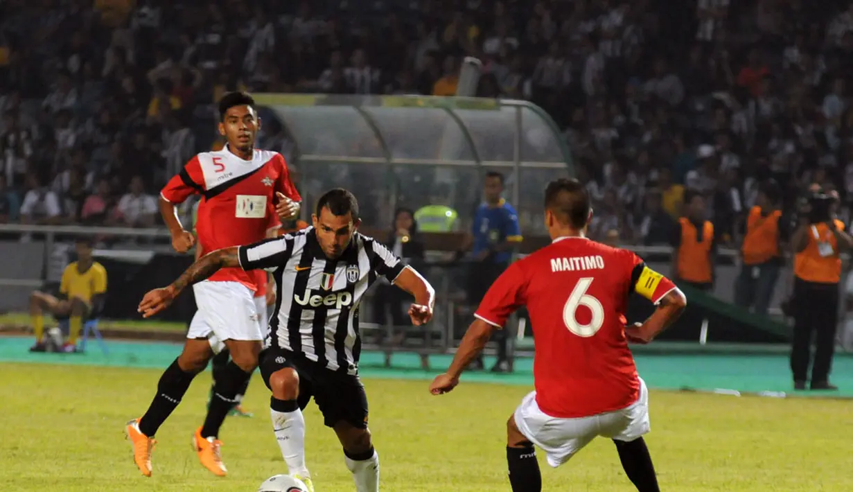 Pemain depan Juventus, Carlos Tevez (tengah), mencoba melewati kawalan Kapten Tim ISL All Stars, Raphael Maitimo, saat berlaga di Stadion GBK Jakarta, (6/8/2014). (Liputan6.com/Helmi Fithriansyah)