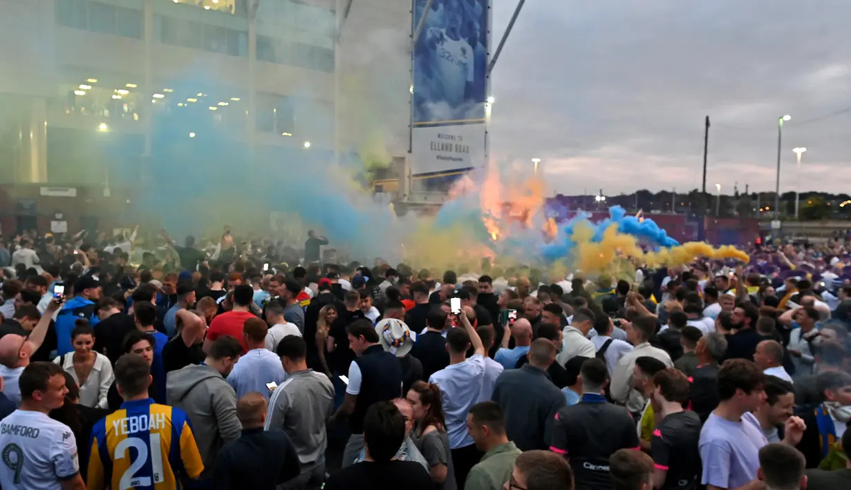 Suporter Leeds United merayakan keberhasilan timnya yang sukses kembali ke kompetisi Premier League di Elland Road, Leeds, Sabtu (18/7/2020). Leeds United dipastikan promosi ke Premier League musim 2020/2021 usai West Brom kalah 1-2 atas Huddersfield Town. (AFP/Paul Ellis)