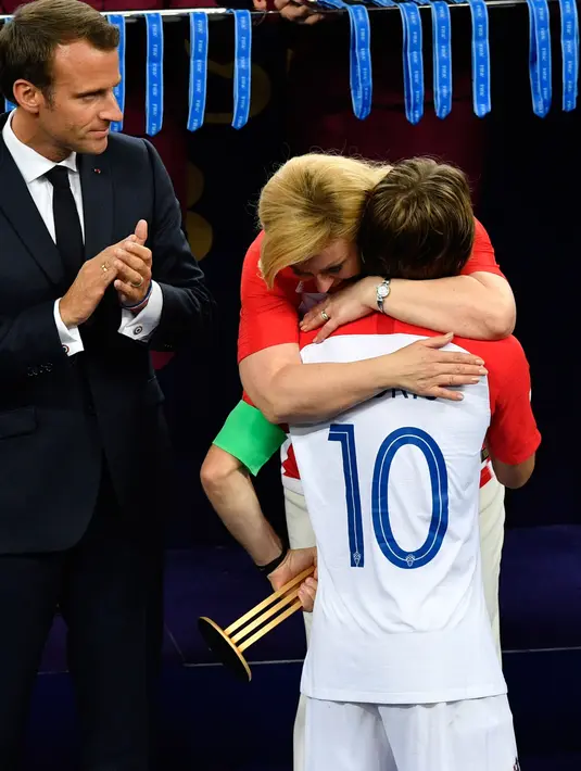 Presiden Kroasia, Kolinda Grabar-Kitarovic memeluk Kapten timnas Kroasia, Luka Modric saat penyerahan medali dan trofi Piala Dunia 2018 di Luzhniki Stadium, Minggu (15/7). Kroasia harus puas menjadi runner-up usai kalah 2-4 dari Prancis. (AFP/FRANCK FIFE)