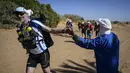 Warga menyemangati peserta lomba lari Marathon des Sables ke-34 tahap kedua di Gurun Sahara, Maroko, Senin (8/4). Marathon des Sables ke-34 diikuti hampir seribu peserta dari 50 negara. (JEAN-PHILIPPE KSIAZEK/AFP)