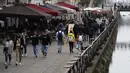 Orang-orang berjalan di sepanjang kanal di distrik Naviglio di Milan, Senin (26/4/2021). Italia kembali dibuka secara bertahap pada hari Senin setelah enam bulan memberlakukan lockdown untuk menghambat penyebaran corona Covid-19. (AP Photo/Antonio Calanni)