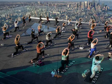 Praktisi yoga menghadiri kelas di Edge Observation Deck, Manhattan, New York, Amerika Serikat, Kamis (17/6/2021). Edge Observation Deck disebut sebagai 'dek langit luar ruang tertinggi di Belahan Barat'. (Ed JONES/AFP)