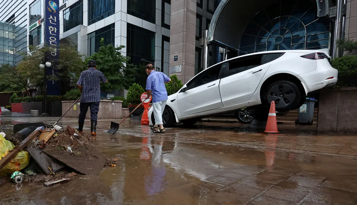 Sebuah mobil yang rusak akibat banjir terlihat di jalan setelah hujan deras di distrik Gangnam, Seoul pada Selasa (9/8/2022). Di distrik Gangnam yang mewah dan sangat terkonsentrasi, beberapa bangunan tanpa listrik dan telah terendam air, sementara mobil, bus, dan stasiun kereta bawah tanah terendam, membuat orang-orang terdampar. (YONHAP / AFP)