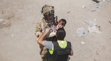 Tentara AS membawa seorang anak di pos pemeriksaan selama evakuasi di Bandara Internasional Hamid Karzai di Kabul, Jumat (20/8/2021). Sejumlah ibu Afghanistan berupaya menyerahkan bayi-bayi mereka pada tentara asing yang berjaga di bandara. (Staff Sgt. Victor Mancilla/U.S. Marine Corps via AP)