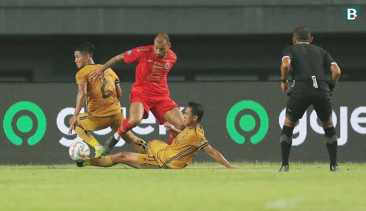 Pemain Persija Jakarta, Gustavo Almeida, diadang pemain Bhayangkara FC, Sani Rizki dan Putu Gede pada laga BRI Liga 1 di Stadion Patriot Candrabhaga, Bekasi, Senin (27/11/2023). Kedua tim bermain sama kuat 2-2. (Bola.com/M Iqbal Ichsan)