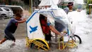 Seorang komuter mengangkat kakinya agar tetap kering saat ia menaiki becak roda tiga di Metropolitan Manila, Filipina, Jumat (20/7). Banjir menyebabkan siswa sekolah diliburkan selama tiga hari. (AP Photo/Bullit Marquez)