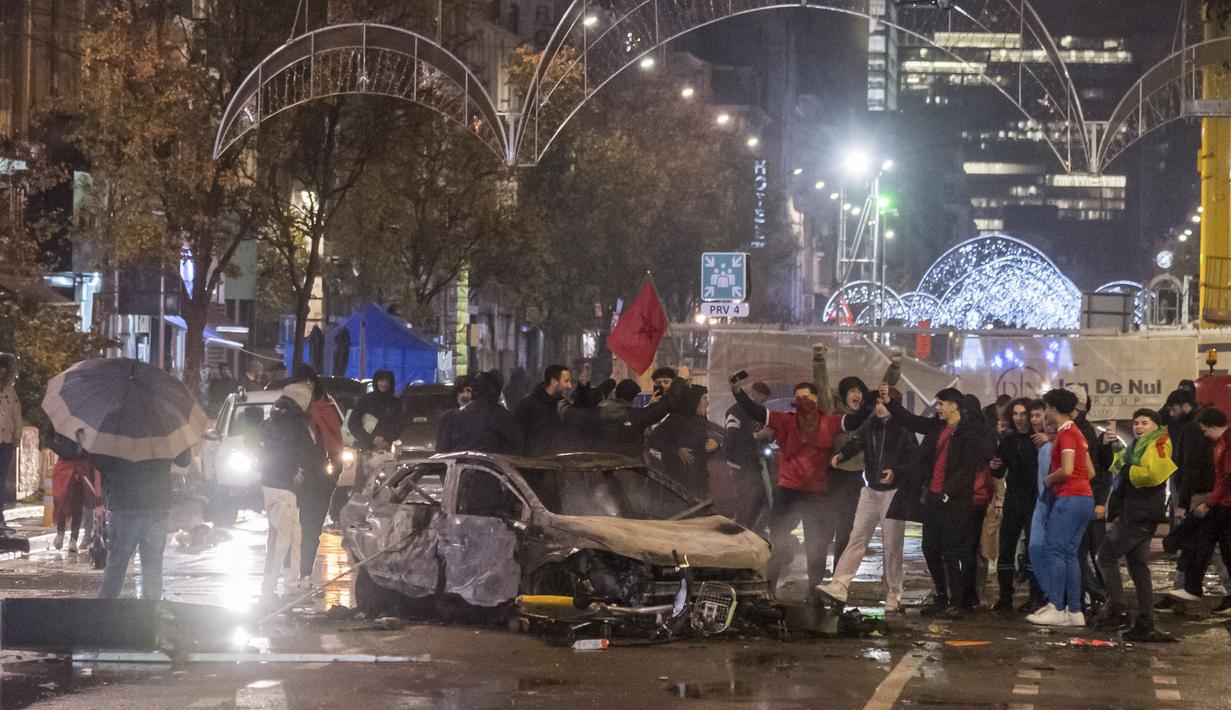 Para suporter itu emosi dan beramai-ramai turun ke jalan untuk melampiaskan kekesalannya dengan cara melempari, merusak dan membakar benda-benda di sekitarnya termasuk mobil. (AP/Geert Vanden Wijngaert)