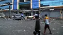 Warga berjalan melewati sebuah mobil yang tertimpa puing bangunan runtuh akibat gempa 6,5 SR yang melanda Surigao City, Pulau Mindanao, Filipina (11/2). (AFP/Erwin Mascarinas)