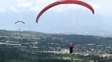 Seorang paraglider lepas landas dari lereng bukit di Puncak, Bogor, Jawa Barat, Kamis (2/12/2021). Destinasi wisata alam Bukit Paralayang Puncak Bogor sangat cocok untuk dikunjungi pada liburan akhir pekan bersama keluarga, sahabat maupun pasangan tercinta. (Goh Chai Hin/AFP)