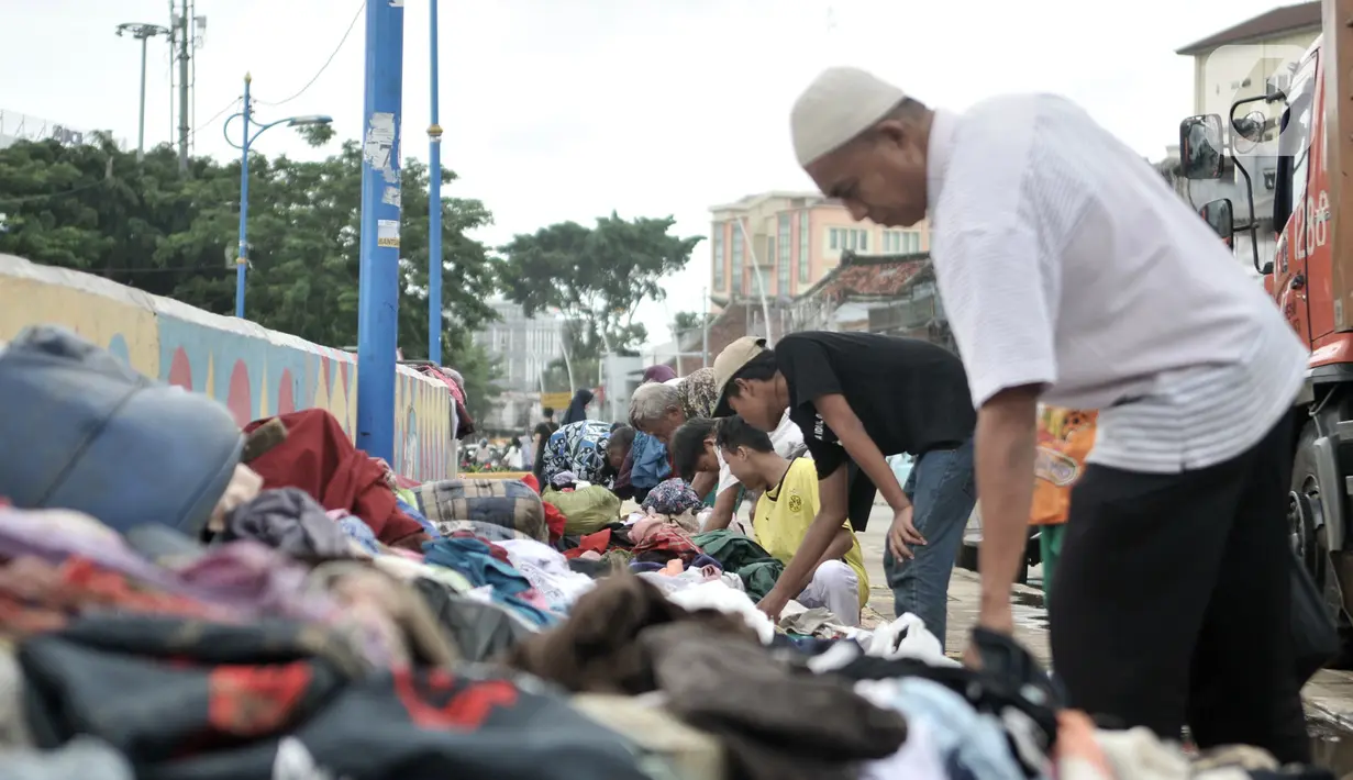 Warga korban banjir saat memilih pakaian sumbangan yang ditempatkan di pinggir Kali Ciliwung, Kampung Pulo, Jakarta Timur, Senin (6/1/2020). Banjir menyebabkan ratusan warga di Kampung Pulo kehilangan pakaian akibat rusak dan hanyut. (merdeka.com/Iqbal S. Nugroho)