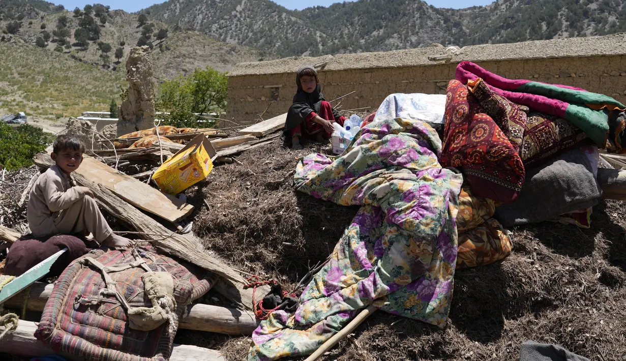 Anak-anak Afghanistan duduk di antara barang-barang mereka yang diselamatkan setelah gempa bumi di desa Gayan, di provinsi Paktika, Afghanistan, Jumat, 24 Juni 2022. Provinsi Paktika terkena dampak paling parah dan PBB berjuang keras untuk menyediakan tempat penampungan darurat serta bantuan makanan. (AP Photo/Ebrahim Nooroozi)