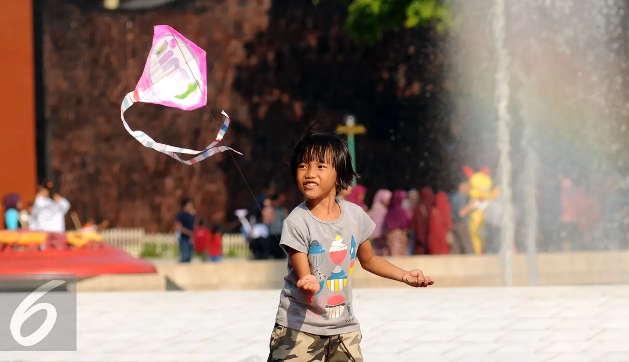 Seorang anak berusaha menerbangkan layang layang saat bermain di Lapangan Monumen Tugu Pancasila TMII, Jakarta, Jumat (8/7). TMII masih menjadi lokasi favorit warga menghabiskan libur hari raya. (Liputan6.com/Helmi Fithriansyah)