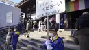 Penjaga keamanan memegang tanda untuk mengontrol pengunjung yang berjalan untuk berdoa memohon keberuntungan selama "hatsumode" atau kunjungan pertama tahun ini ke kuil atau wihara, di kuil Kawasaki Daishi di Kawasaki, dekat Tokyo, Senin, 2 Januari 2023. (AP Photo/Eugene Hoshiko)