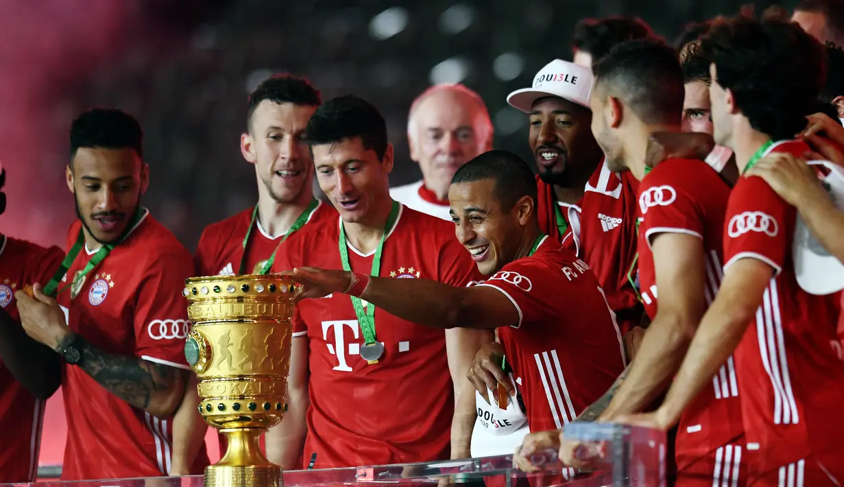 Pemain Bayern Munchen Thiago Alcantara menyentuh trofi juara Piala Jerman (DFB Pokal) usai mengalahkan Bayer Leverkusen di Olympic Stadium, Berlin, Jerman, 4 Juli 2020. (Photo by ANNEGRET HILSE/POOL/AFP)