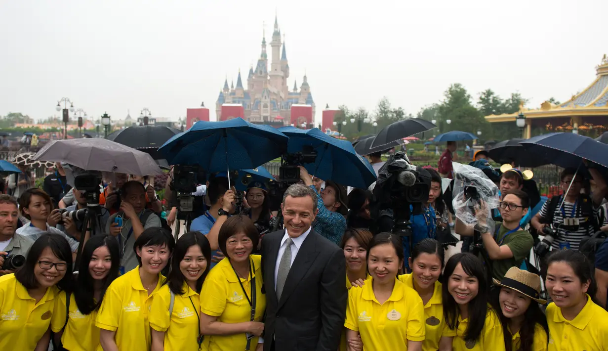 CEO Walt Disney, Bob Iger berpose dengan relawan di depan Shanghai Disney Resort di Shanghai, Tiongkok, (16/6). Taman bermain ini dibanjiri pengunjung di hari pertama pembukaan. (AFP Photo/Johannes Eisele)