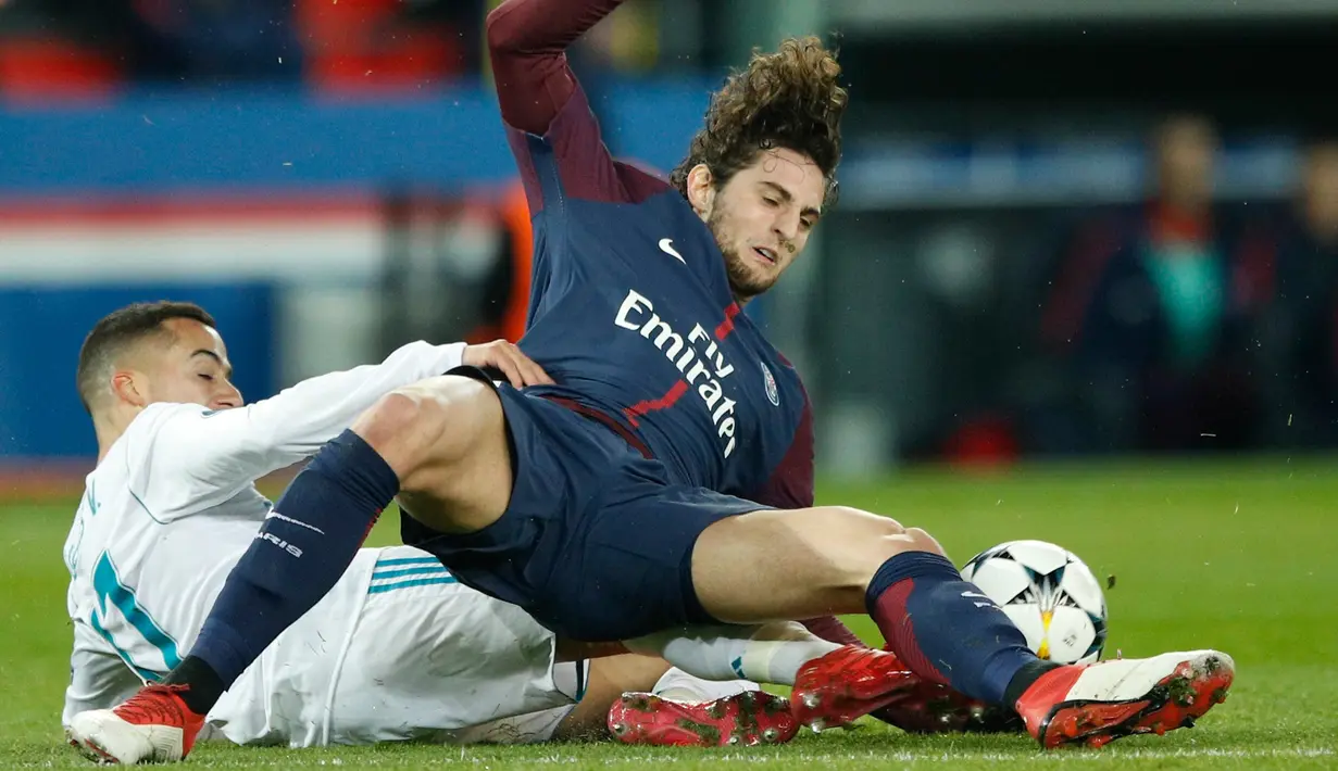 Pemain Real Madrid Lucas Vazquez melakukan sliding kepada Adrien Rabiot saat pertandingan Liga Champions leg kedua di stadion Parc des Princes di Paris (6/3). Real Madrid menang 2-1 atau unggul agregat 5-2 atas PSG. (AP/ Francois Mori)
