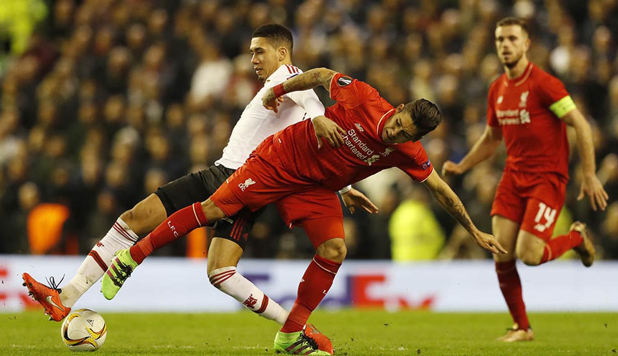 Gelandang Liverpool, Roberto Firmino, berebut bola dengan bek MU, Chris Smailing. Jika ingin lolos MU butuh kemenangan dengan selisih tiga gol saat laga leg kedua di Stadion Old Trafford. (Reuters/Phil Noble)