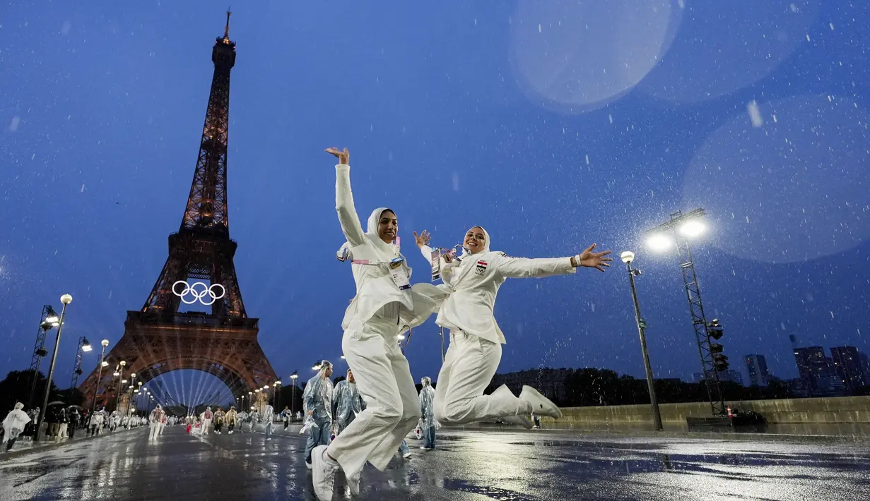 Dua orang atlet Mesir melompat di depan menara Eiffel saat acara pembukaan Olimpiade 2024 di Paris, Sabtu (27/7/2024).  (AP Photo/Andy Wong)