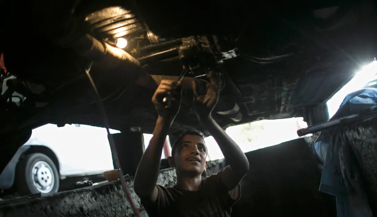 Mohammed (15) memperbaiki mobil di sebuah bengkel di Rafah, Selatan Jalur Gaza, 21 November 2016. Akibat perang di wilayah itu, kurang lebih setengah dari penduduk Gaza yang  berjumlah 1,9 juta jiwa hidup di bawah garis kemiskinan. (SAID KHATIB/AFP)