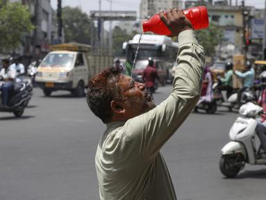 Seorang pria menyiramkan air ke wajahnya saat musim panas di Hyderabad, India, Sabtu, 14 Mei 2022. Suhu di New Delhi mencapai 45 Derajat Celcius. (AP Photo/Mahesh Kumar A.)