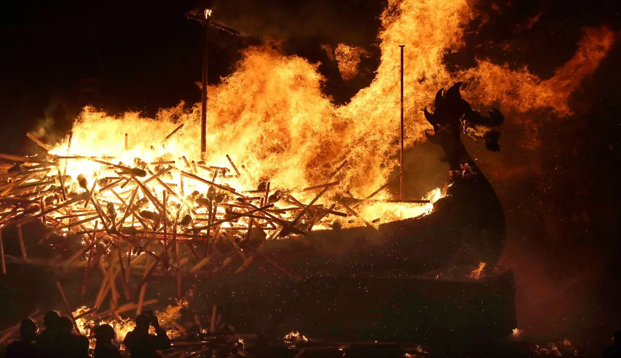 Anggota Jarl Squad membakar replika longship / kapal perang bangsa Viking saat festival Up Helly Aa Viking di Lerwick, Kepulauan Shetland, Skotlandia (31/1). Sedikitnya ada 5.000 wisatawan yang datang untuk menonton. (Jane Barlow/PA via AP)