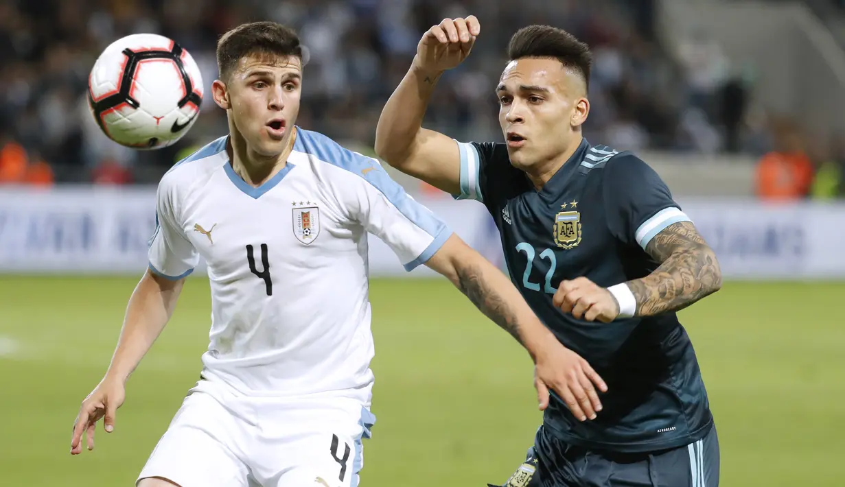 Bek timnas Uruguay, Giovani Gonzalez berebut bola dengan pemain timnas Argentina Lautaro Martinez dalam laga persahabatan di Stadion Bloomfield, Tel Aviv, Israel, Senin (18/11/2019). Skor berakhir 2-2, dengan penalti Lionel Messi menghindarkan timnas Argentina  dari kekalahan. (EMMANUEL DUNAND/AFP)