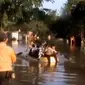 Para siswa ini harus naik perahu karet untuk bisa menyebrangi genangan air yang sudah mencapai ketinggian 70 cm.