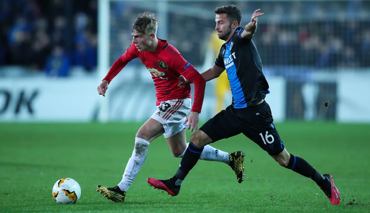 Bek kiri Manchester United, Brandon Williams, berebut bola dengan pemain Club Brugge, Siebe Schrijvers dalam leg pertama babak 32 besar Liga Europa di Jan Breydelstadion, Kamis (20/2/2020). Manchester United gagal meraih hasil maksimal usai ditahan imbang Club Brugge 1-1. (AP/Francisco Seco)