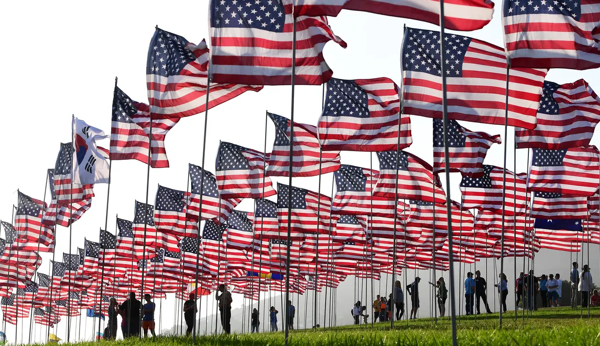 Orang-orang membantu pengibaran bendera AS untuk peringatan 20 tahun serangan 9/11 di Pepperdine University di Malibu, California, Rabu (8/9/2021). Selama 14 tahun, universitas itu memperingati tragedi 11 September 2001 dengan mengibarkan sekitar 3.000 bendera Amerika. (Frederic J. BROWN/AFP)