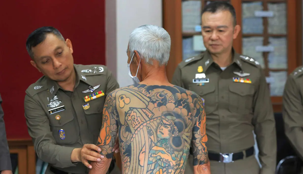 Petugas menunjukkan tato Mantan bos Yakuza asal Jepang, Shigeharu Shirai di sebuah kantor polisi saat konferensi pers di Lopburi, Thailand, Kamis, (11/1). Pria 72 tahun ini ditangkap setelah 14 tahun menjadi buronan. (AP Photo)