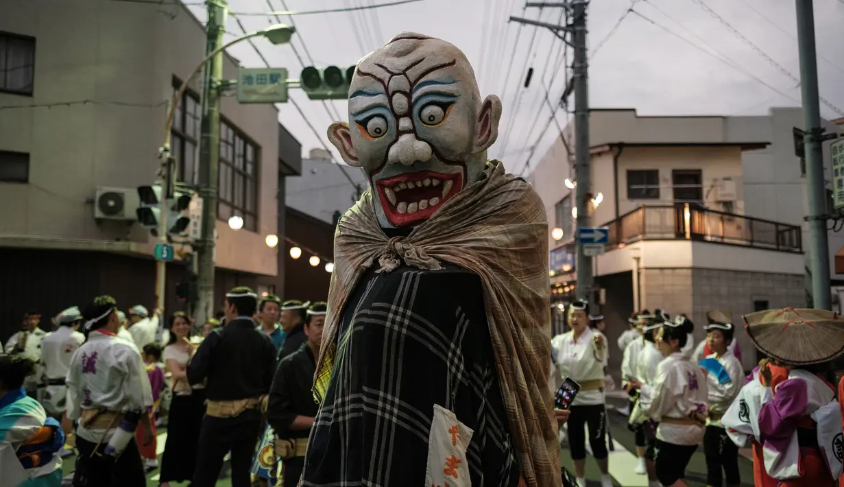 Peserta mengenakan kostum hantu saat festival Awa Odori di Kota Miyoshi, Jepang (16/8). Acara ini biasanya dimulai pada siang hari, namun pertunjukan utamanya baru dimulai pada petang hingga malam hari. (AFP Photo/Yasuyoshi Chiba)