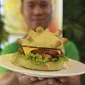 Pemilik restoran Hoang Tung menunjukkan burger berbentuk virus corona COVID-19 di Hanoi, Vietnam, Rabu (25/3/2020). Sebuah restoran di Hanoi membuat kreasi baru mereka yang disebut ‘Burger Corona’. (AP Photo/Hau Dinh)