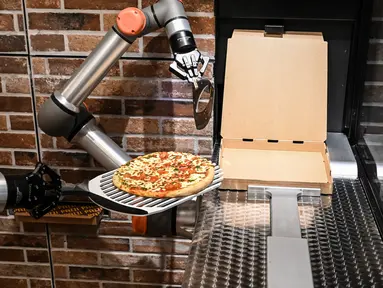 Foto yang diambil pada 1 Juli 2021 menunjukkan "Pazzi", robot pembuat pizza yang sedang bekerja di sebuah restoran di Paris. Robot pembuat pizza dari startup Paris Pazzi tersebut mulai beroperasi di jantung kota Paris pada 5 Juli 2021 (BERTRAND GUAY/AFP)