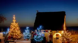 Pohon Natal dan Sinterklas menghiasi pintu masuk pantai di Haffkrug, Jerman utara, Senin (20/12/2021). (AP Photo/Michael Probst)