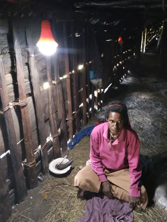 Seorang warga menikmati Lampu Tenaga Surya Hemat Energi (LTSHE) di desa terpencil Papua. Pada tahun 2018 Kementerian ESDM akan memasang LTSHE untuk 167.064 rumah di 1.230 desa, tersebar di 18 provinsi (Liputan6.com/HO/Hadi M Djuraid)