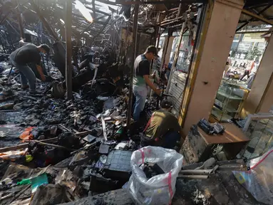 Sejumlah pedagang mengais puing dan sisa barang dagangan yang hangus terbakar di Pasar Taman Puring, Jakarta Selatan, Selasa (29/7/2025). (merdeka.com/Arie Basuki)