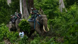 Anggota polisi militer bersama penjaga taman nasional melakukan patroli keliling hutan dengan bantuan gajah di kawasan hutan Ulue Masen, provinsi Aceh, Sabtu (27/4/2019). Patroli keliling tersebut guna menjaga kelestarian alam dan satwa liar dari ancaman kepunahan. (CHAIDEER MAHYUDDIN/AFP)