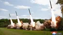 Foto-foto media KCNA menunjukkan setidaknya empat roket ditembakkan dari kendaraan peluncur saat Kim menyaksikan dari pos pengamatan. (STR / KCNA VIA KNS / AFP)