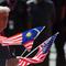 Presiden Donald Trump mengangkat bendera Malaysia dan Amerika Serikat dalam upacara penyambutan setibanya di Bandara Internasional Kuala Lumpur, Minggu (26/10/2025) untuk menghadiri KTT ke-47 ASEAN. (Dok. Hasnoor Hussain/Pool Photo via AP)&nbsp;&nbsp;&nbsp;