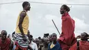 Dua pria melompat untuk mencapai tali selama mengikuti Olimpiade Maasai 2018 di Kimana, Kenya (15/12). Olimpiade Maasai ini untuk menghentikan berburu singa. (AFP Photo/Yasuyoshi Chiba)