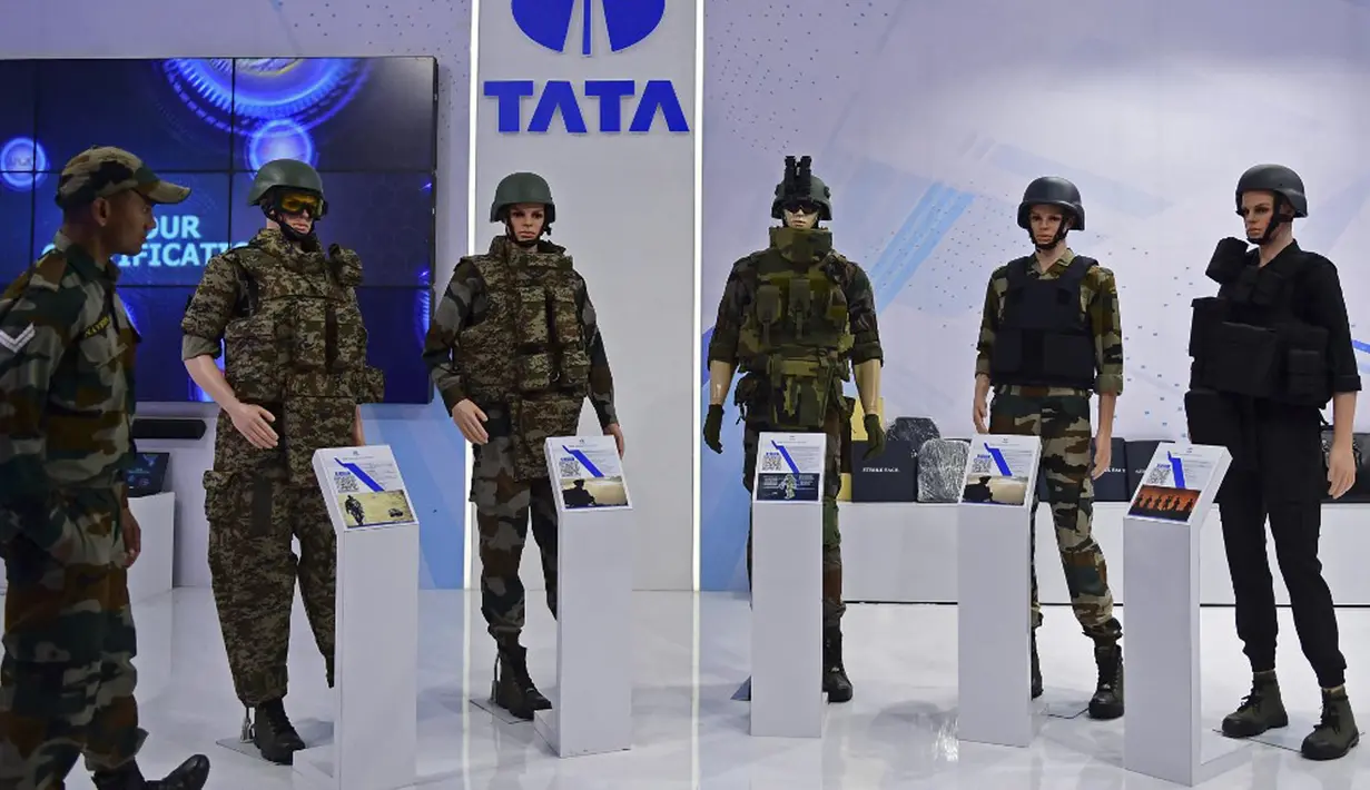 Seorang tentara India (kiri) melihat berbagai pakaian tempur yang dipajang di Tata Aerospace and Defense dome selama Defense Expo 2022 di Gandhinagar, India, 18 Oktober 2022. Defense Expo 2022 ini akan berlangsung selama lima hari. (Sam PANTHAKY/AFP)