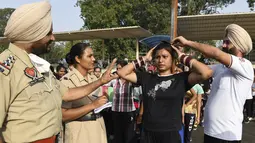 Petugas polisi Punjab mengukur tinggi badan seorang calon polisi wanita saat pelatihan calon polisi Punjab di Amritsar, India, Senin (28/6/2021). (AFP/Narider Nanu)