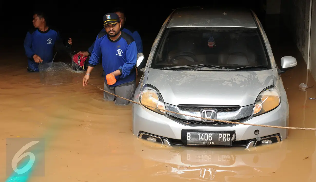 Petugas berusaha mengevakuasi mobil dari parkir basement sebuah pertokoan di Jalan Kemang Raya, Minggu (28/8). Sejumlah kendaraan terendam air di kawasan Kemang Raya pasca hujan deras di Jakarta pada Sabtu (27/8). (Liputan6.com/Helmi Fithriansyah)