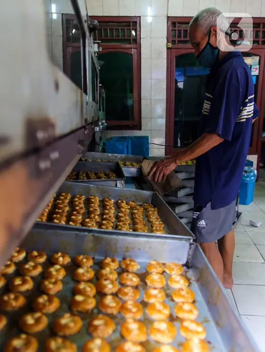 Pekerja memasukkan adonan kue ke oven di industri pembuatan kue kering Pusaka Kwitang, Jakarta, Kamis (30/4/2020). Kue kering yang dijual seharga Rp480 ribu per kaleng itu pada bulan Ramadan tahun ini mengalami penurunan produksi hingga 500 kaleng akibat pandemi COVID-19. (Liputan6.com/Johan Tallo)